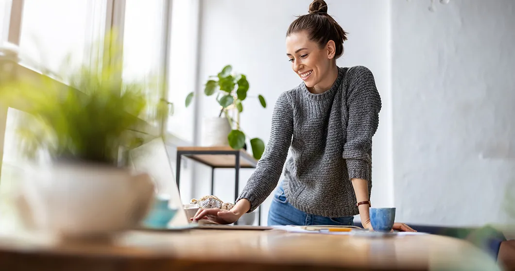 Junge Frau, die vor einem Fenster am Notebook arbeitet